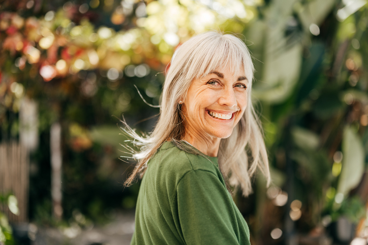 Happy older woman in front of trees